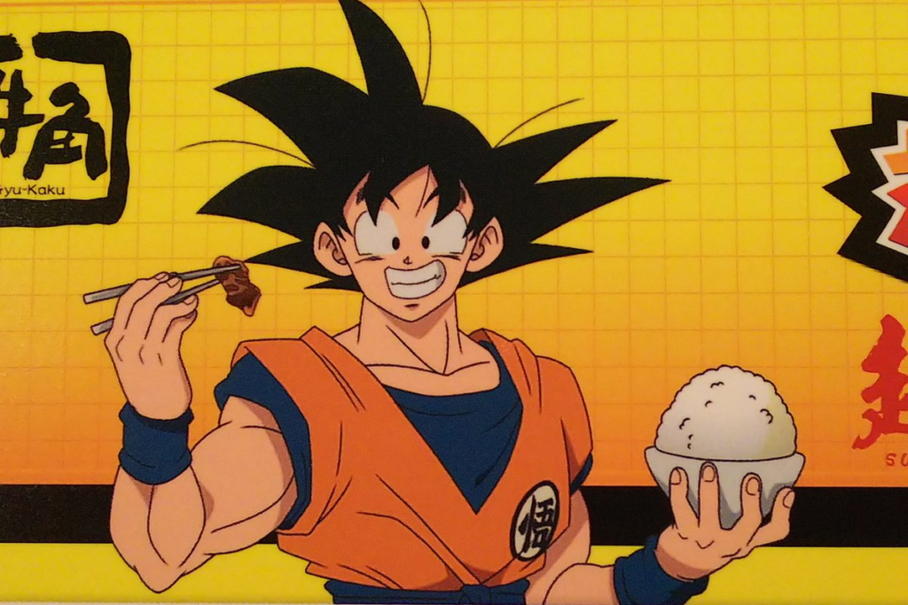 Goku mangia carne grigliata con le bacchette e tiene in mano una ciotola di riso bianco